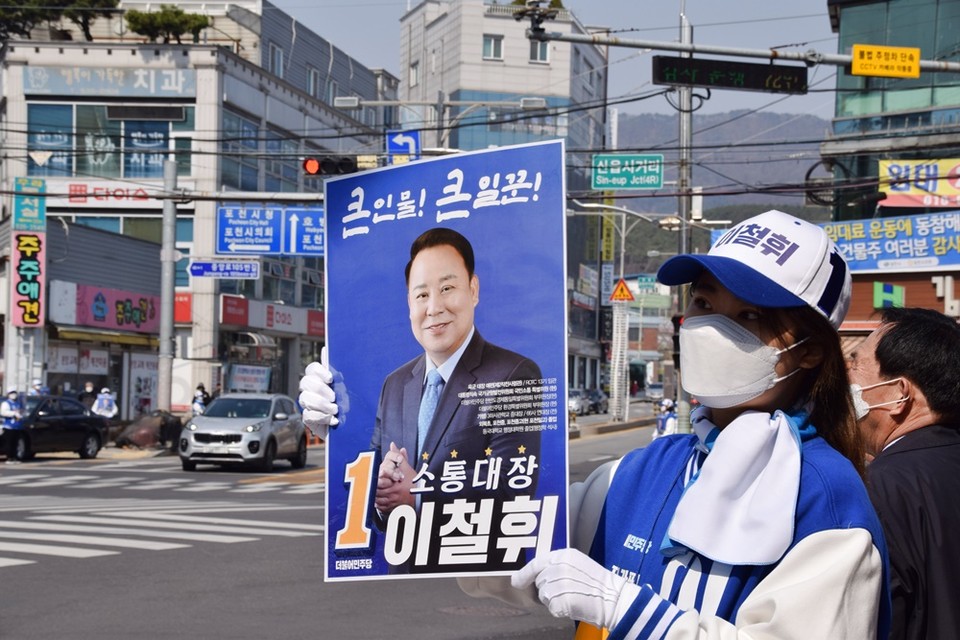이철휘 후보 선거운동원이 지나가는 차량을 향해 이 후보 지지 피켓을 보여주고 있다.