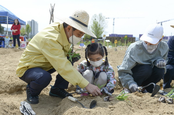 박윤국 포천시장이 소확행 시민텃밭 개장식에 방문, 어린이에게 모종심기 방법을 알려주며 대화하고 있다.
